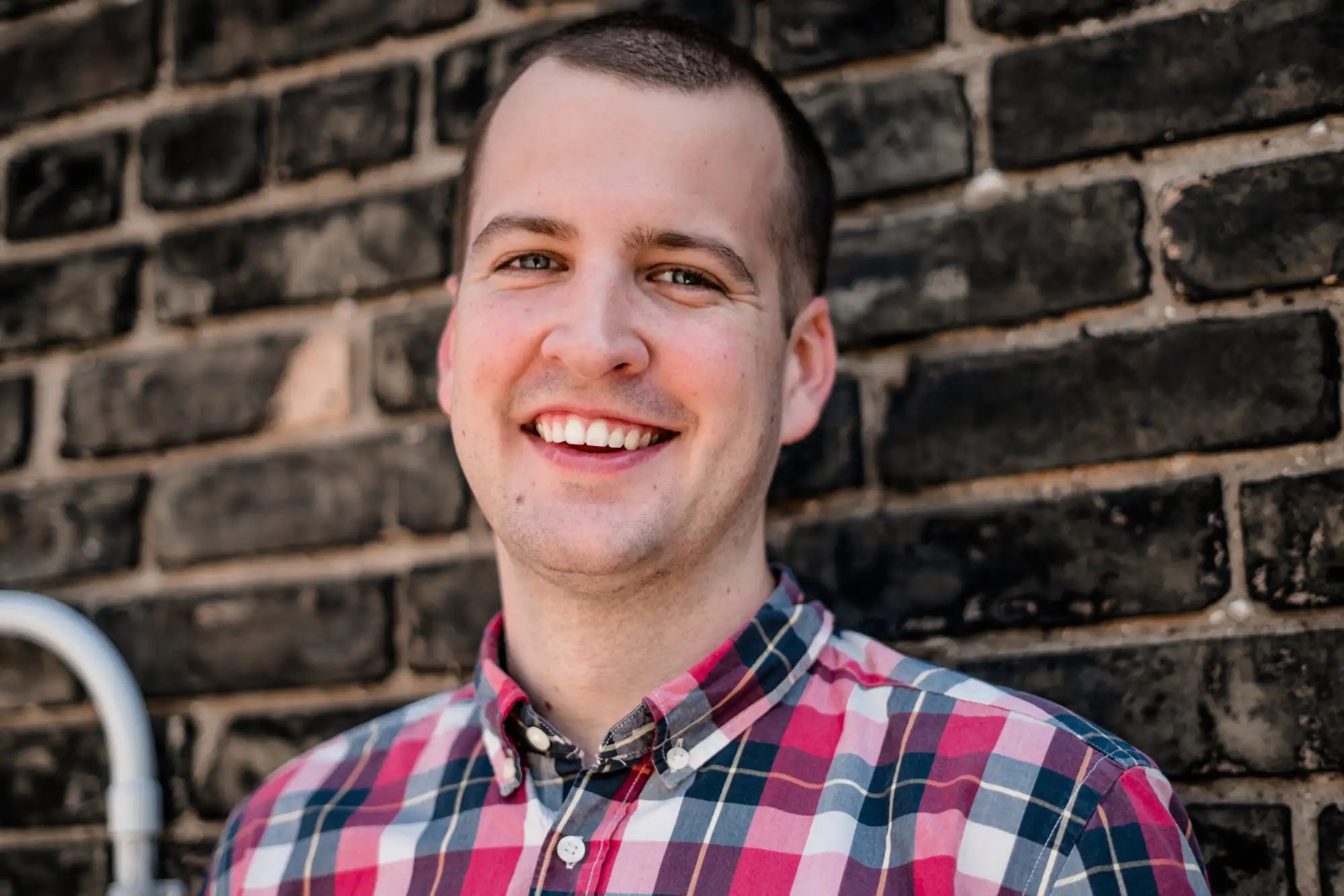 A man wearing a red, blue, and white plaid button-down shirt.