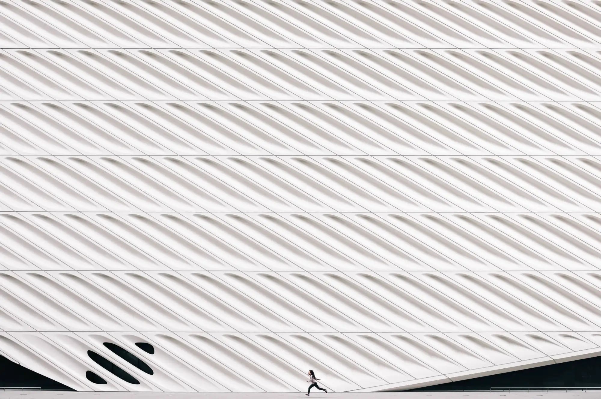 A minimalist white architectural facade with diagonal ribbed panels and a sleek, modern design.