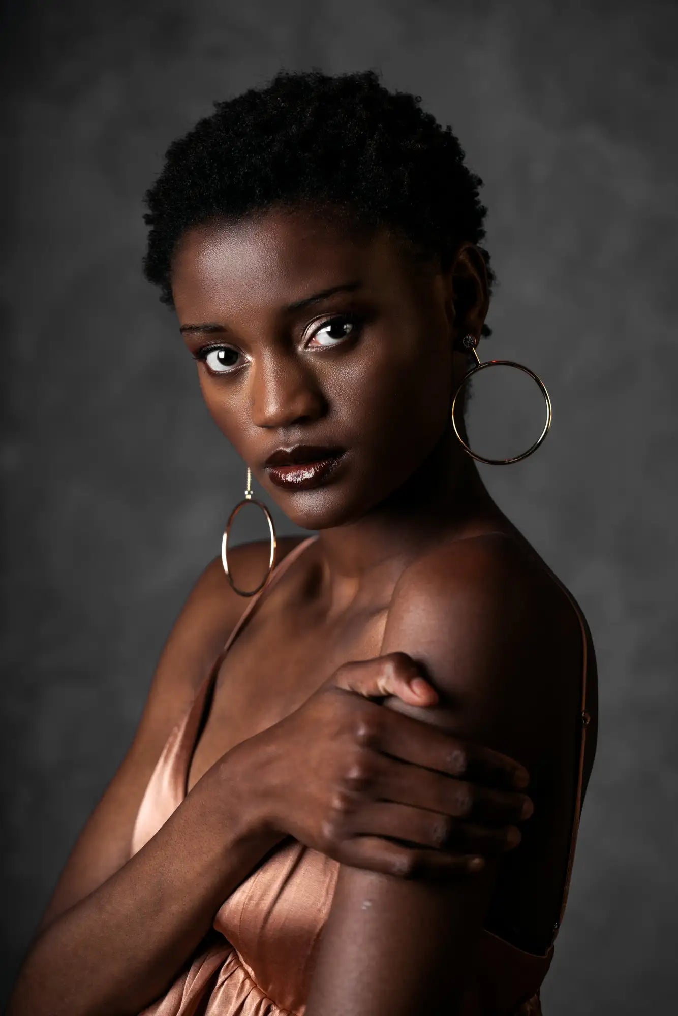 The model wears a pair of large, minimalist hoop earrings with a sleek metallic finish.