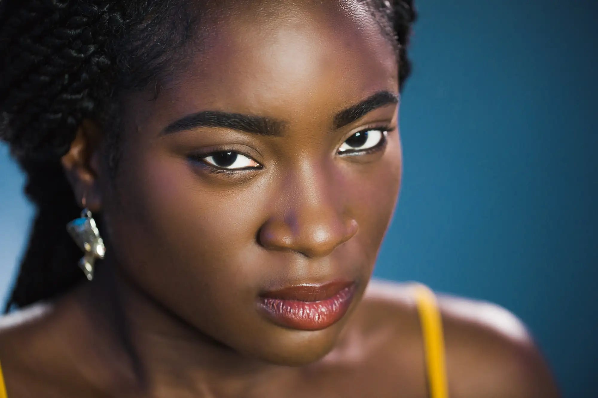 A woman with dark skin and curly hair wearing a yellow top.
